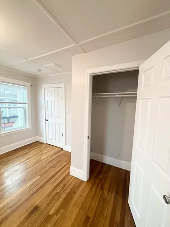 an empty room with wooden floor closet and windows