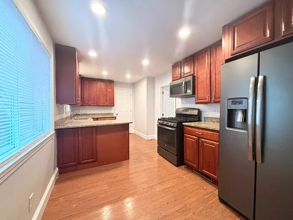 a large kitchen with stainless steel appliances granite countertop a refrigerator sink and cabinets
