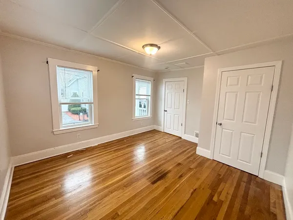 a view of an empty room with wooden floor and a window