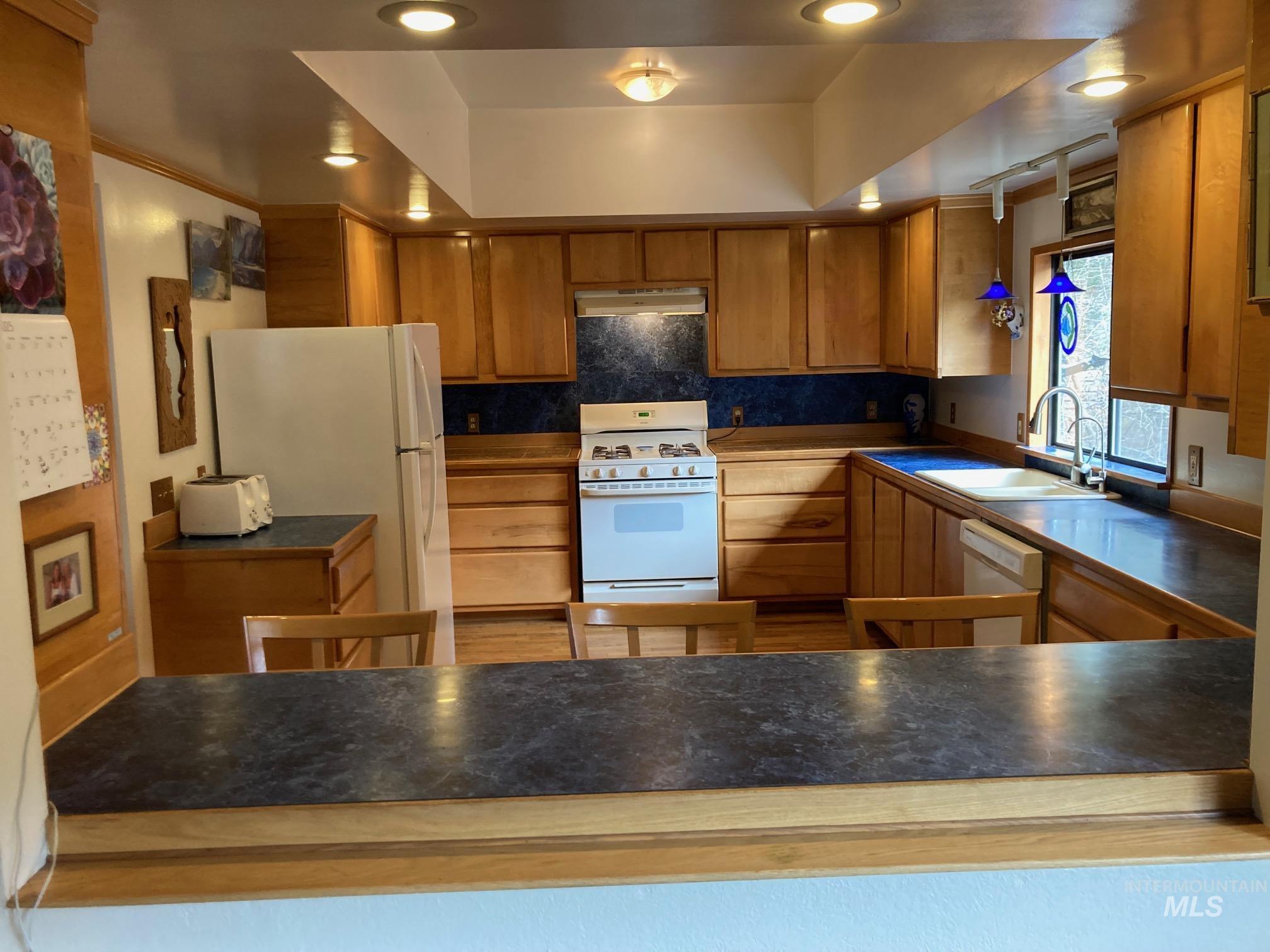266 Falcon Ridge Road Kooskia, ID 83539 - Photo 10 of 50 Well-appointed kitchen featuring wood cabinetry, dark-finish countertops, and a blue tile backsplash