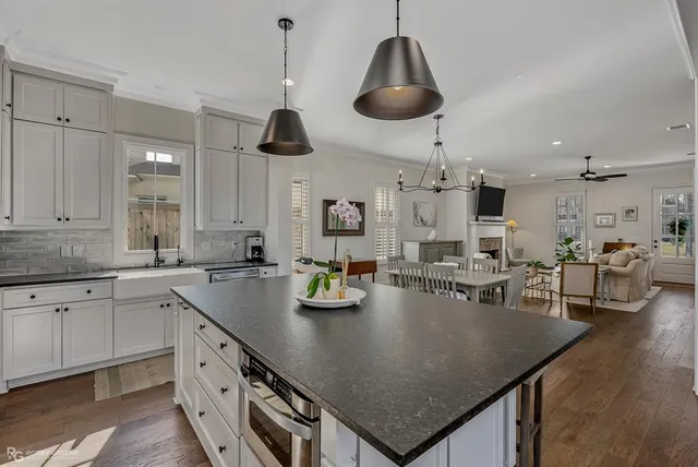 a kitchen with stainless steel appliances granite countertop a sink a stove and living room view