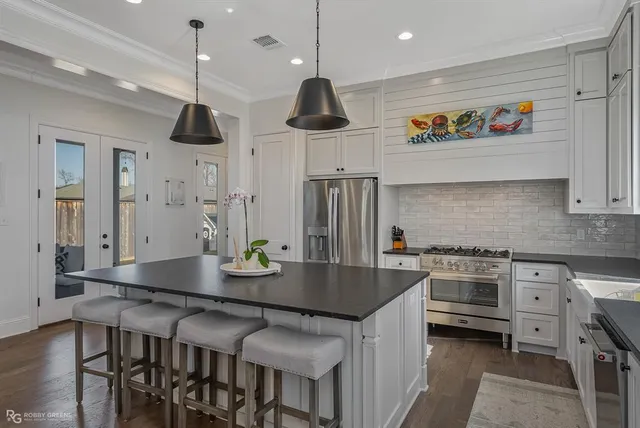 a kitchen with stainless steel appliances granite countertop a stove a sink and a dining table with chairs