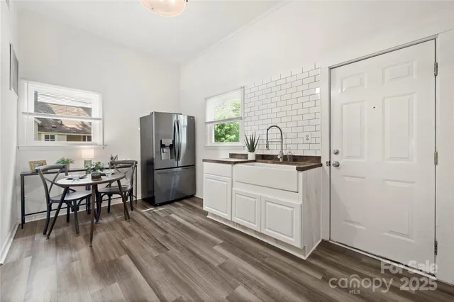 a kitchen with granite countertop a refrigerator a sink a dining table and chairs