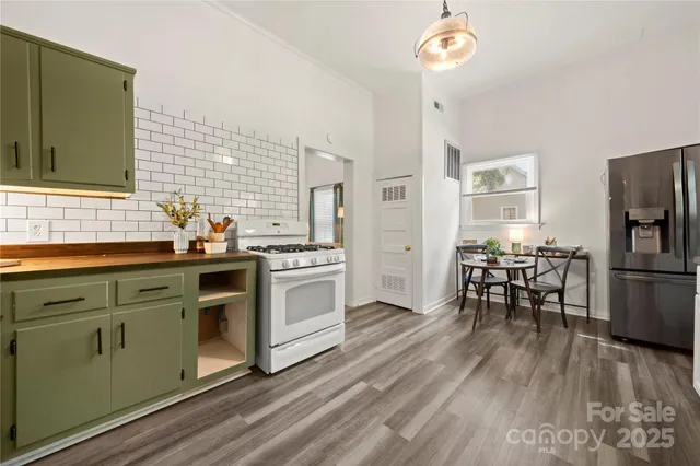 a kitchen with stainless steel appliances a stove a sink dishwasher and a refrigerator with wooden floor