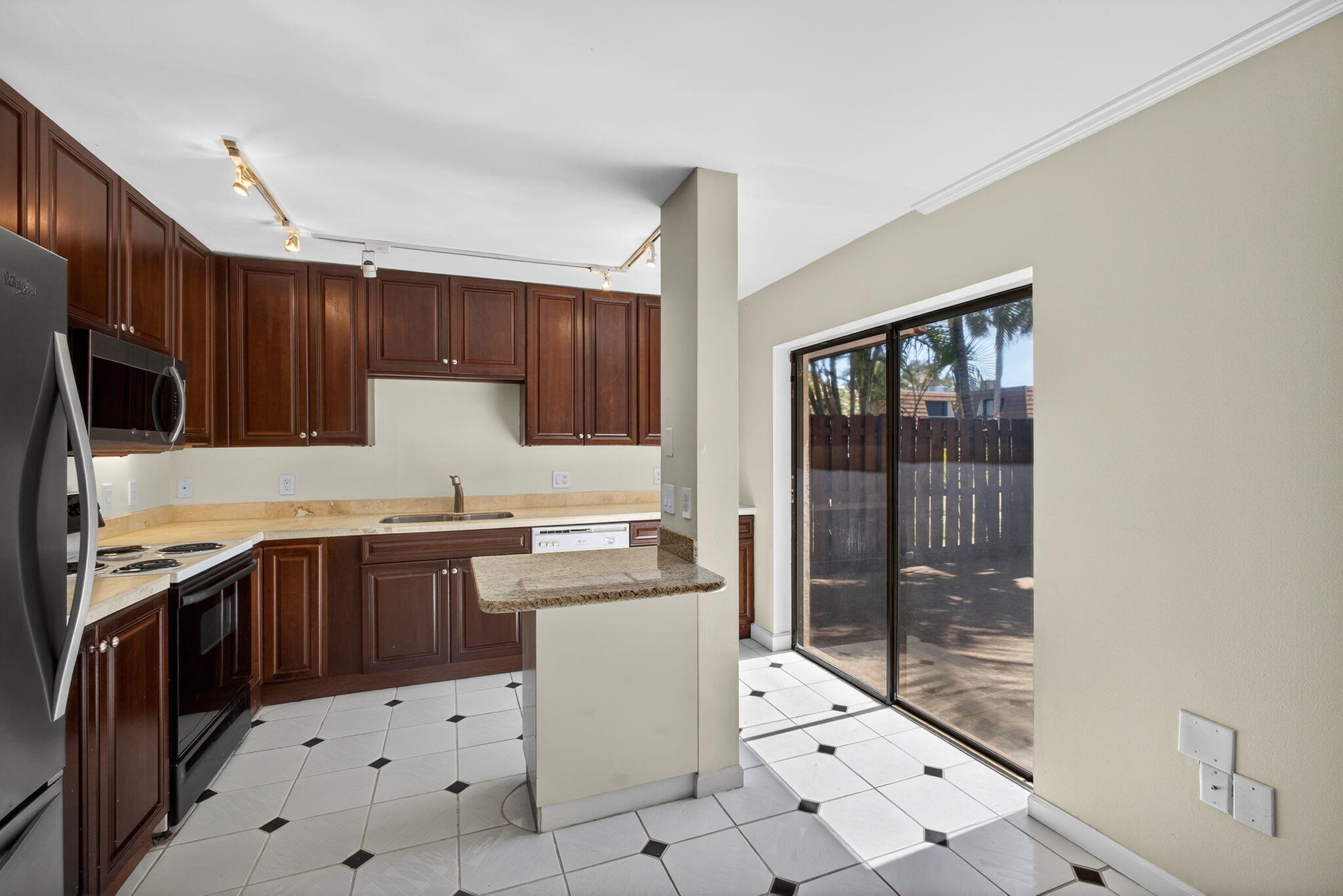 825 Center Street, Unit 9A Jupiter, FL 33458 - Photo 18 of 52 a kitchen with stainless steel appliances granite countertop a stove a sink dishwasher a refrigerator and a oven with wooden cabinets