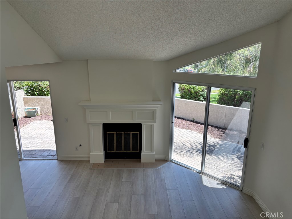 81 Stanford Court, Unit 67 Irvine, CA 92612 - Photo 29 of 30 an empty room with wooden floor a fireplace and windows