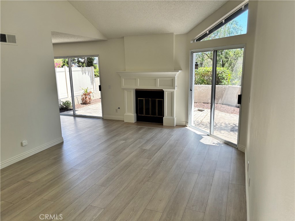 81 Stanford Court, Unit 67 Irvine, CA 92612 - Photo 4 of 30 an empty room with wooden floor fireplace and windows