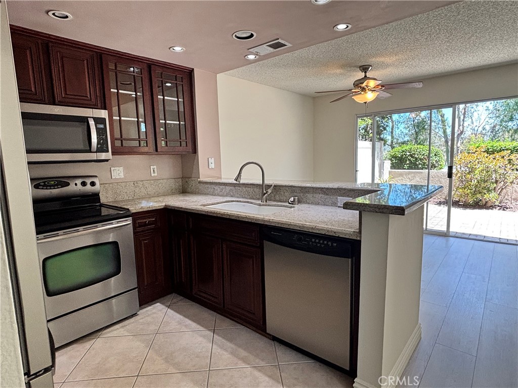 81 Stanford Court, Unit 67 Irvine, CA 92612 - Photo 10 of 30 a kitchen with stainless steel appliances granite countertop a sink stove and microwave