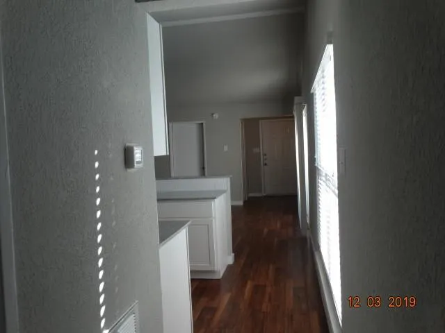 a view of a hallway with wooden floor and a bathroom