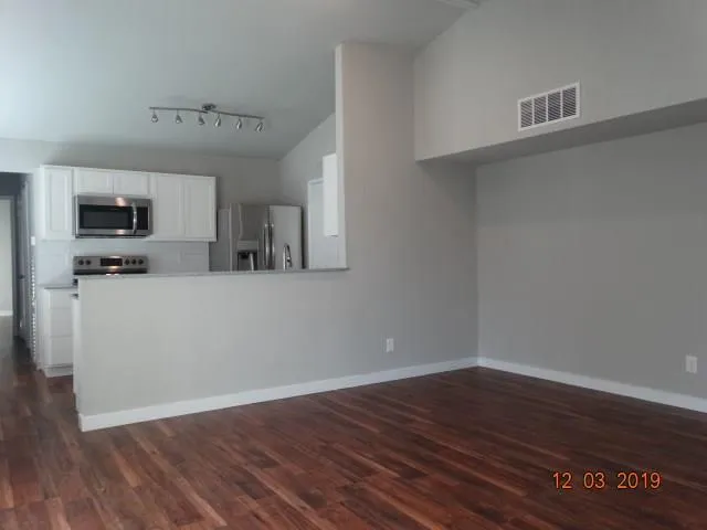 a view of a kitchen with wooden floor and a window