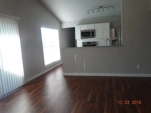 a view of a kitchen with wooden floor and electronic appliances