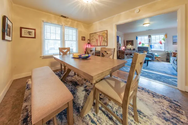 a view of a dining room and livingroom with furniture wooden floor a rug a painting and a chandelier