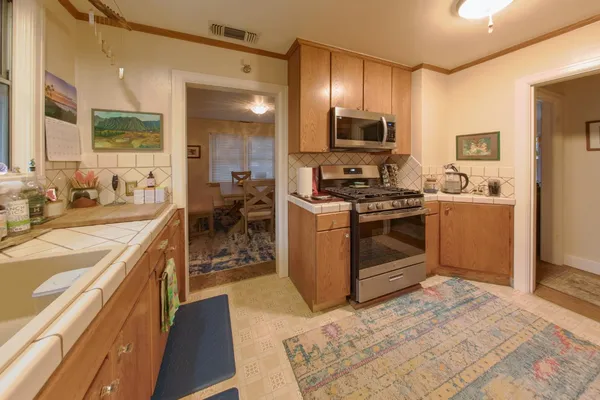 a kitchen with stainless steel appliances granite countertop a stove top oven a sink dishwasher a dining table and chairs with wooden floor