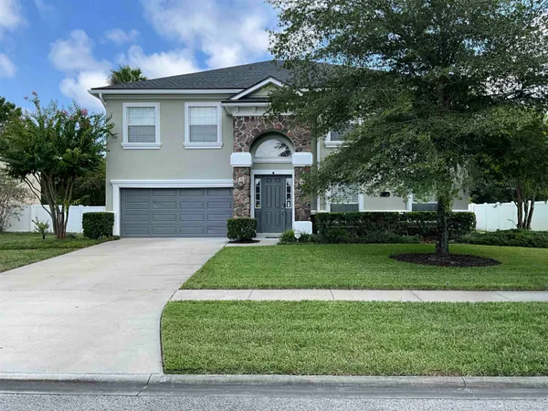 a front view of a house with a yard and trees