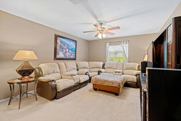 a living room with furniture ceiling fan and a window