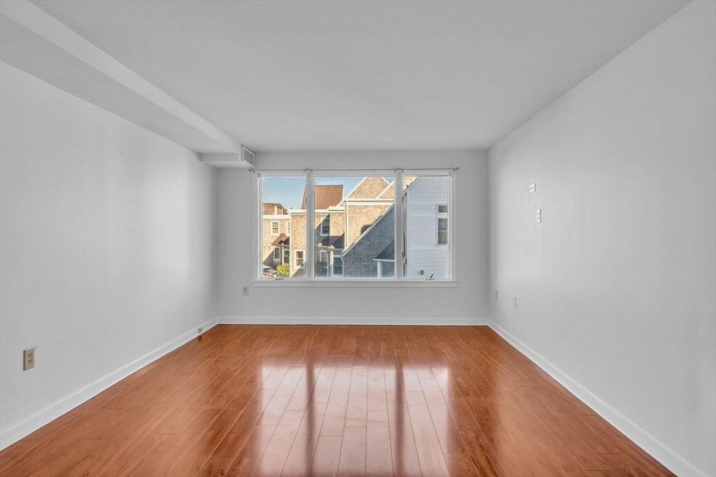 1 Commodore Court, Unit 202 Hull, MA 02045 - Photo 13 of 35 an empty room with wooden floor and windows