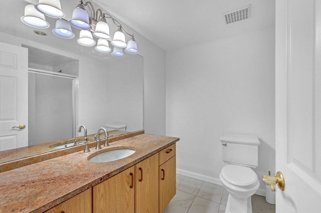 1 Commodore Court, Unit 202 Hull, MA 02045 - Photo 24 of 35 a bathroom with a granite countertop sink a toilet and a mirror