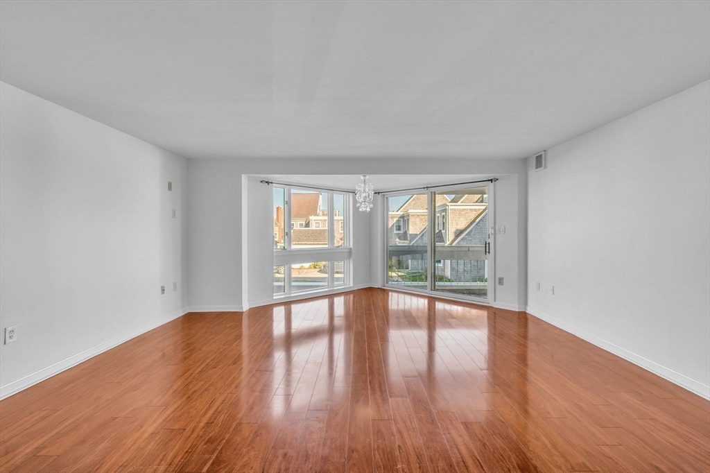 1 Commodore Court, Unit 202 Hull, MA 02045 - Photo 10 of 35 a view of an empty room with wooden floor and a window