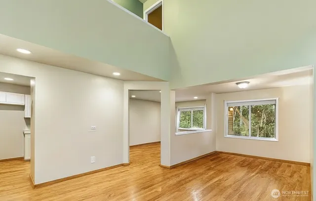 an empty room with wooden floor and windows