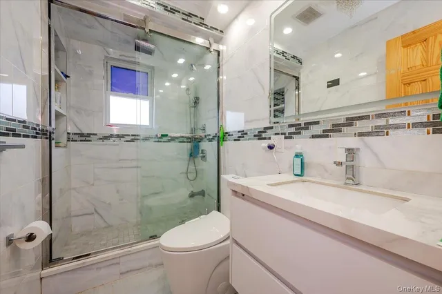 a bathroom with a granite countertop sink mirror vanity and toilet