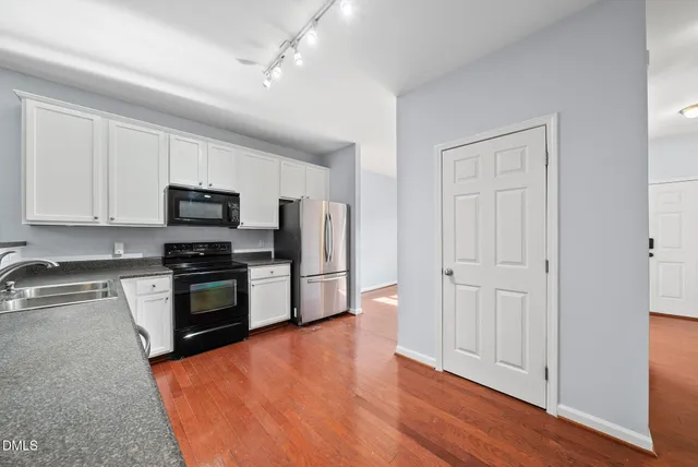 a kitchen with granite countertop a refrigerator and a stove top oven