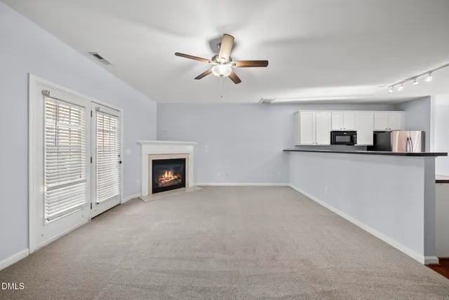 a view of a livingroom with a fireplace a ceiling fan and windows