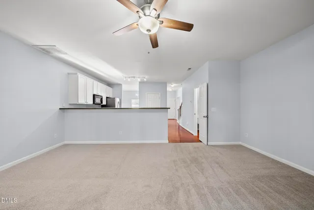 a view of kitchen and empty room with wooden floor