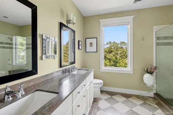 a bathroom with a granite countertop sink toilet and painting on the wall