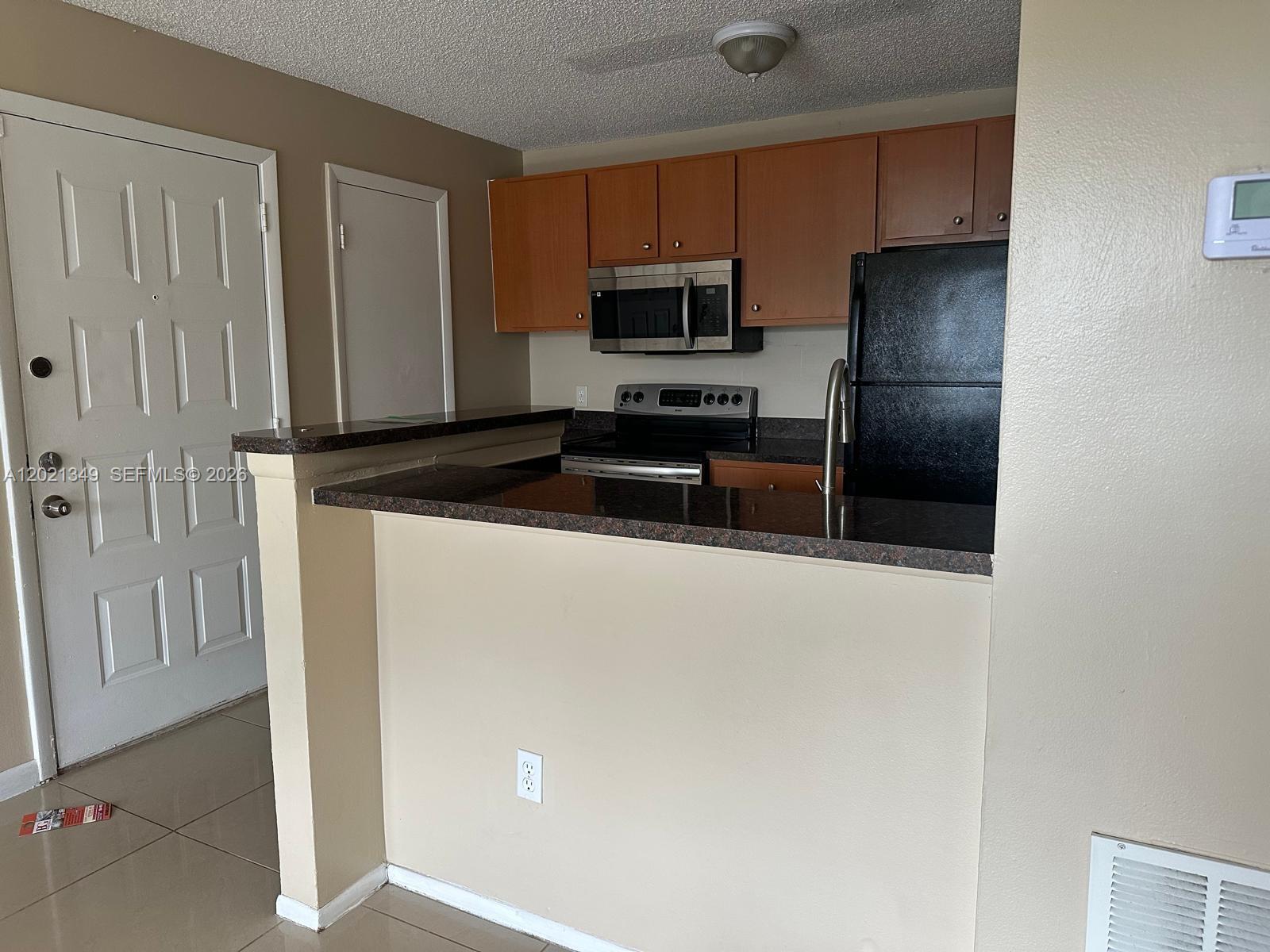 4481 West McNab Road, Unit 37 Pompano Beach, FL 33069 - Photo 10 of 20 a kitchen with granite countertop a refrigerator and a stove top oven
