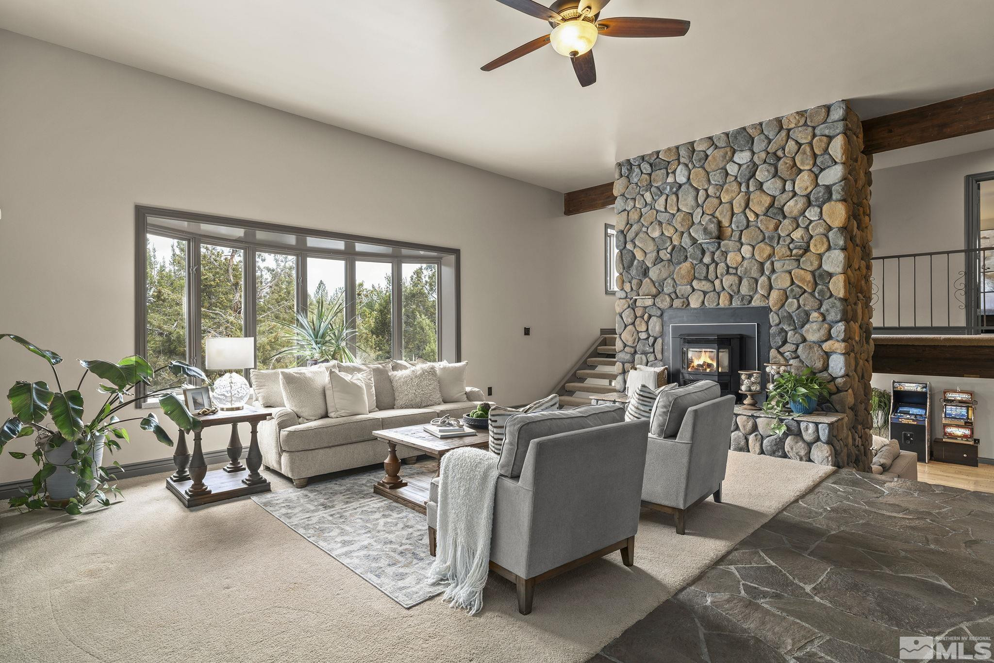 a living room with furniture a fireplace and a floor to ceiling window