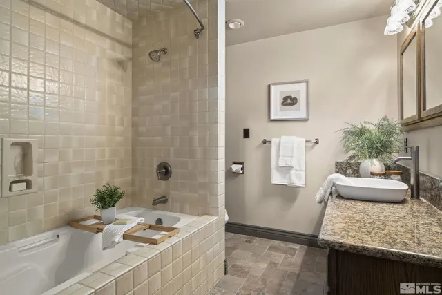 a bathroom with a granite countertop tub sink and mirror