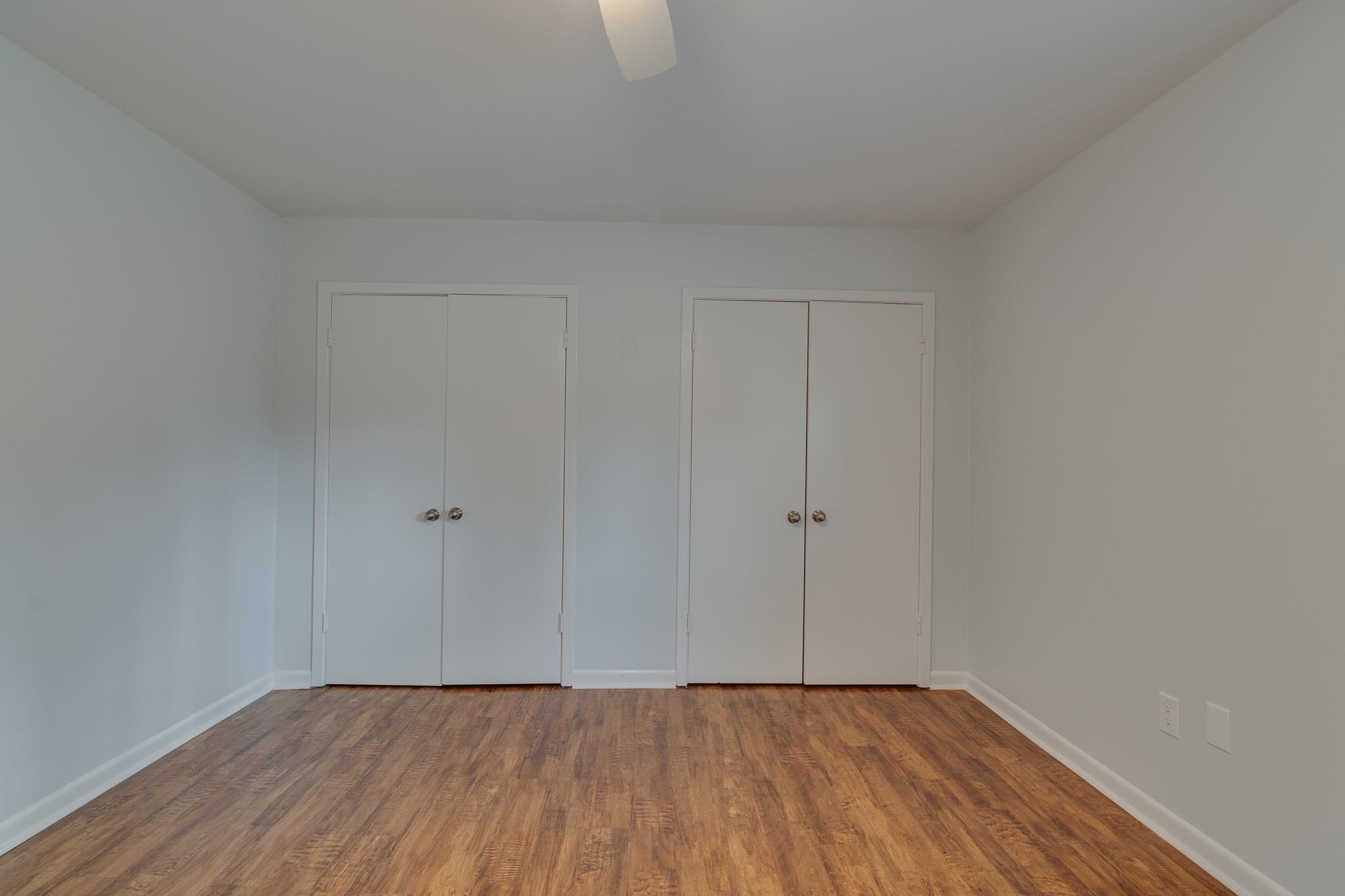 971 June Road, Unit 7 Memphis, TN 38119 - Photo 13 of 23 Unfurnished bedroom featuring baseboards, multiple closets, ceiling fan, and wood finished floors