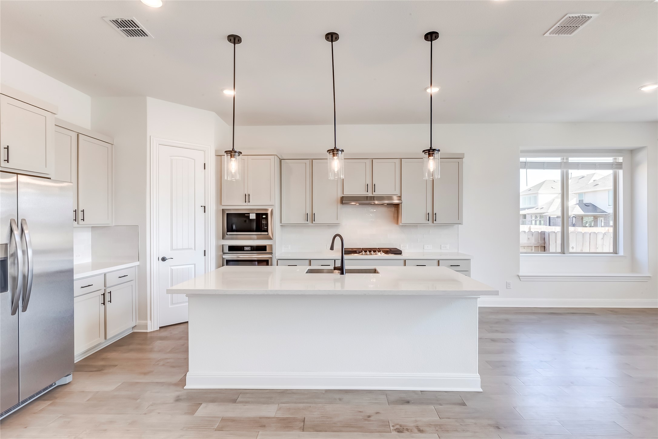 920 Old Gdn Road Leander, TX 78641 - Photo 11 of 39 Kitchen with decorative light fixtures, stainless steel appliances, light wood-type flooring, light stone counters, and recessed lighting