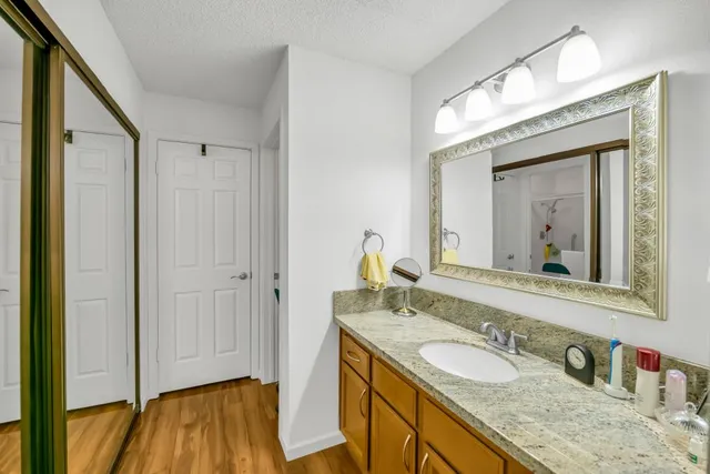 a bathroom with a granite countertop sink a mirror and a shower