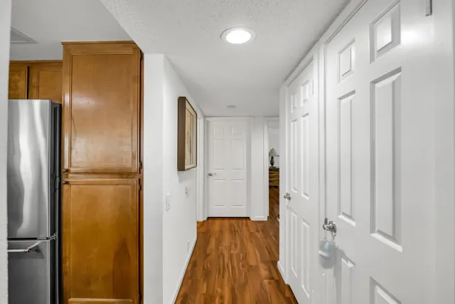 a view of a hallway with wooden floor and cabinets in a kitchen