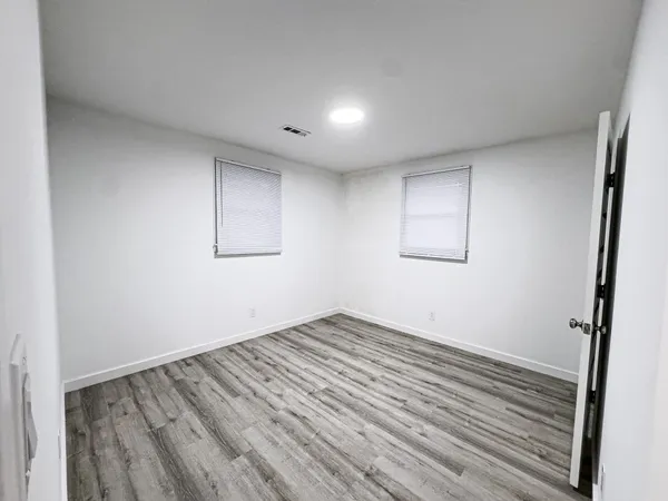 an empty room with wooden floor and windows