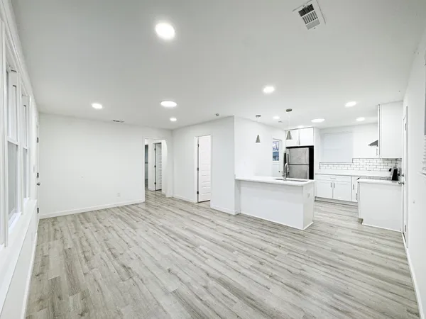 a view of kitchen with kitchen island a sink wooden floor and a refrigerator