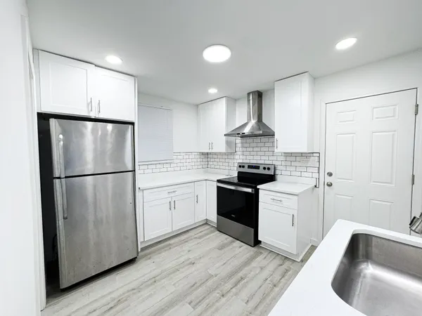 a kitchen with granite countertop a refrigerator stove top oven and sink