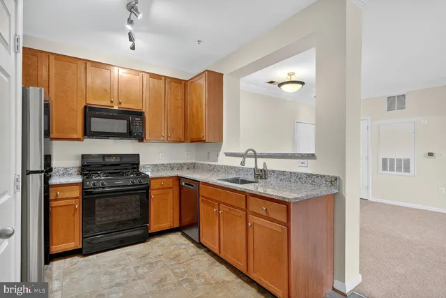 a kitchen with stainless steel appliances granite countertop wooden cabinets stove top oven a sink and dishwasher
