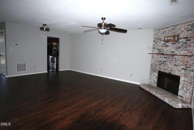 an empty room with wooden floor a fireplace and windows