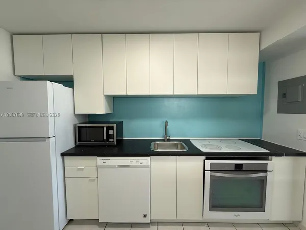 a kitchen with white cabinets and white appliances