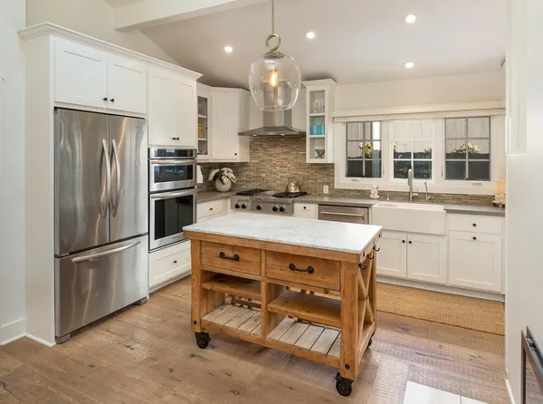 a kitchen with kitchen island wooden cabinets and refrigerator