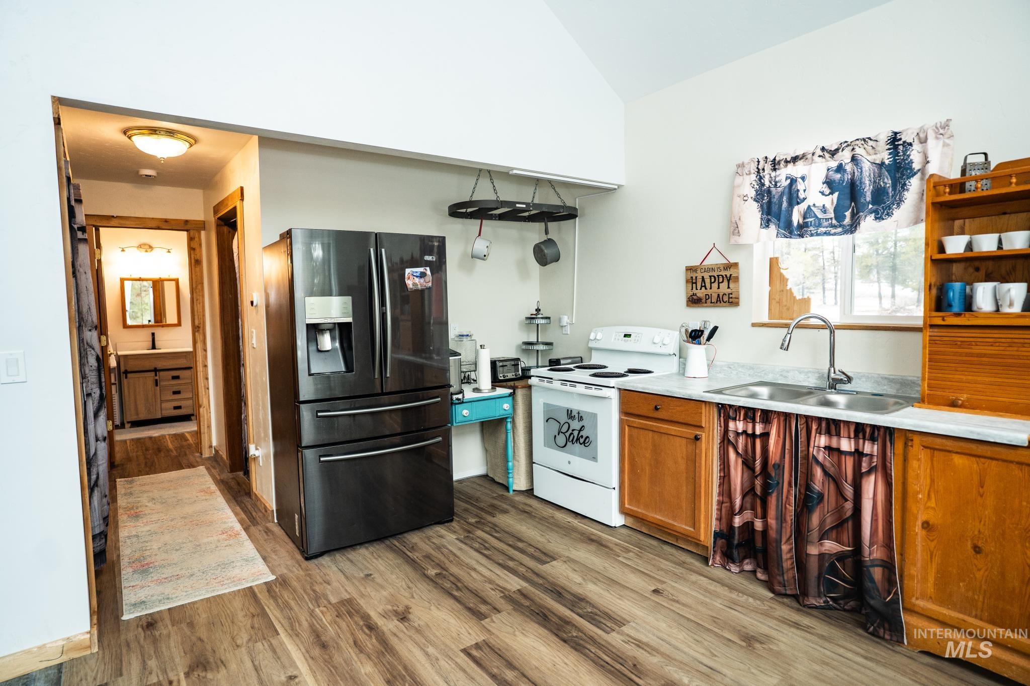 22 West Prospectors Drive Cascade, ID 83611 - Photo 25 of 29 Kitchen featuring stainless steel refrigerator with ice dispenser, white electric range, light countertops, light wood-style floors, and brown cabinetry