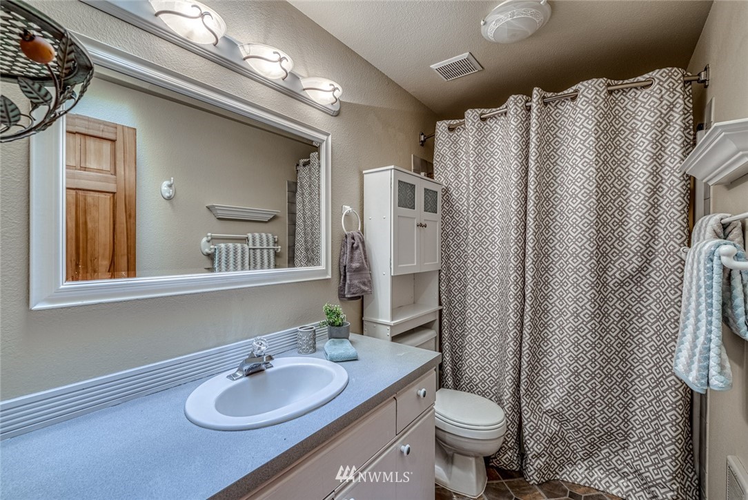 7025 Vandermark Road East Bonney Lake, WA 98391 - Photo 18 of 25 a bathroom with a granite countertop sink toilet and a mirror