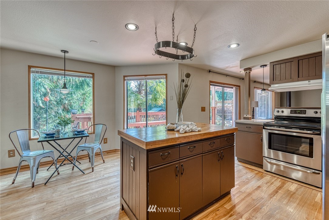 7025 Vandermark Road East Bonney Lake, WA 98391 - Photo 7 of 25 a kitchen with stainless steel appliances granite countertop a stove a refrigerator a sink dishwasher a dining table and chairs with wooden floor