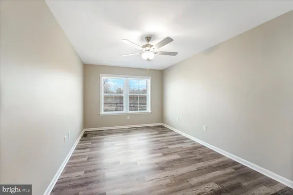 an empty room with wooden floor ceiling fan and windows