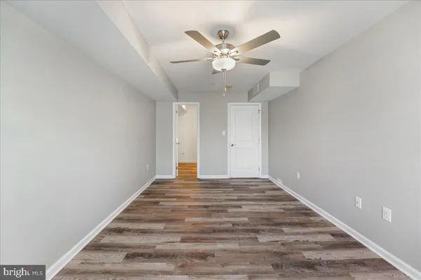 a view of an empty room with chandelier fan and wooden floor