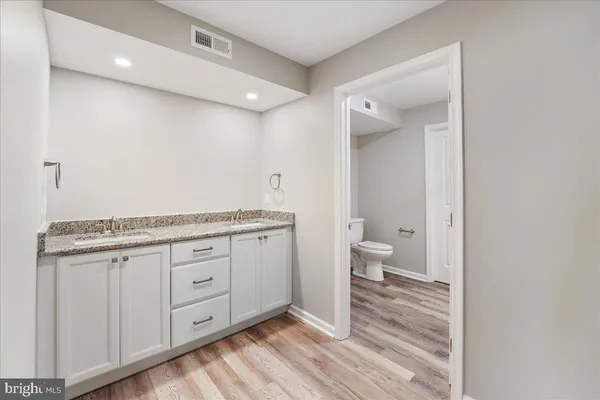 a bathroom with a granite countertop sink a toilet and a mirror