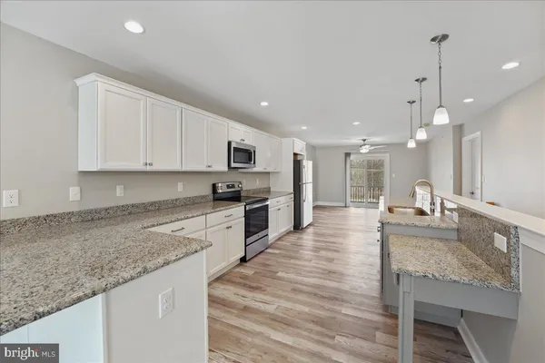 a large kitchen with granite countertop a large counter top stainless steel appliances and cabinets