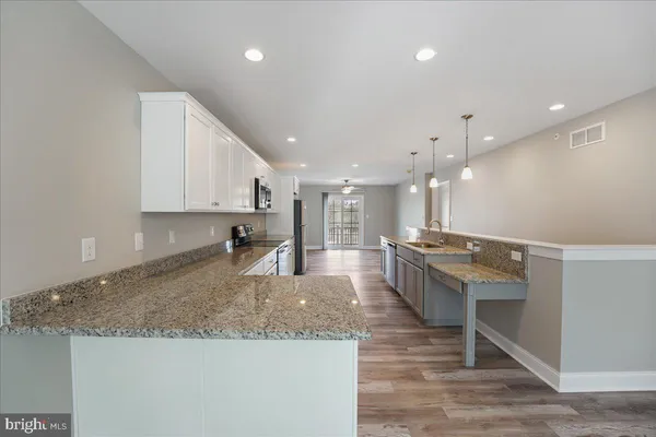 a large kitchen with kitchen island a sink stainless steel appliances and white cabinets